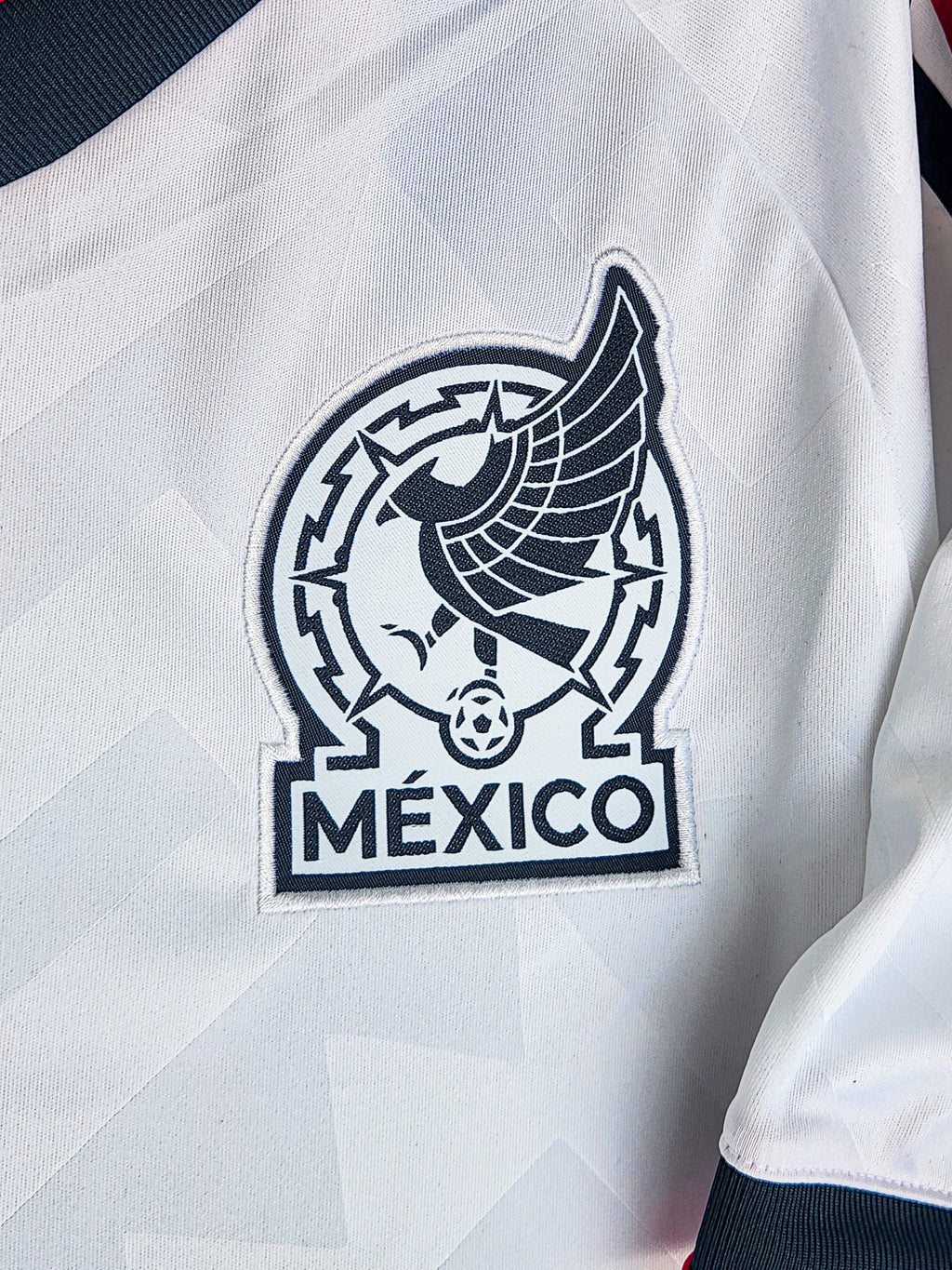Close-up of a white sports jersey with a black eagle emblem and 'México' text.