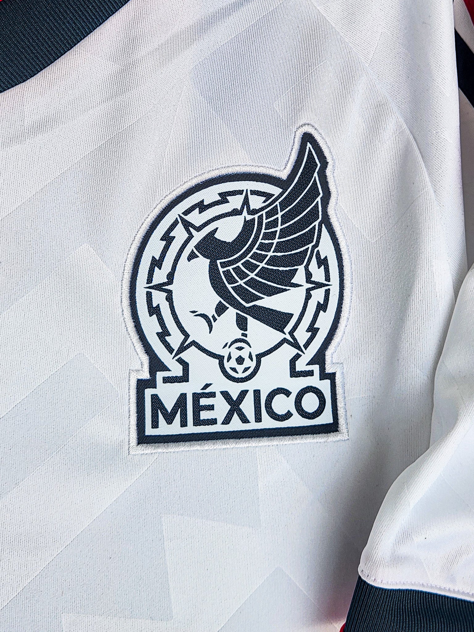 Close-up of a white sports jersey with a black eagle emblem and 'México' text.