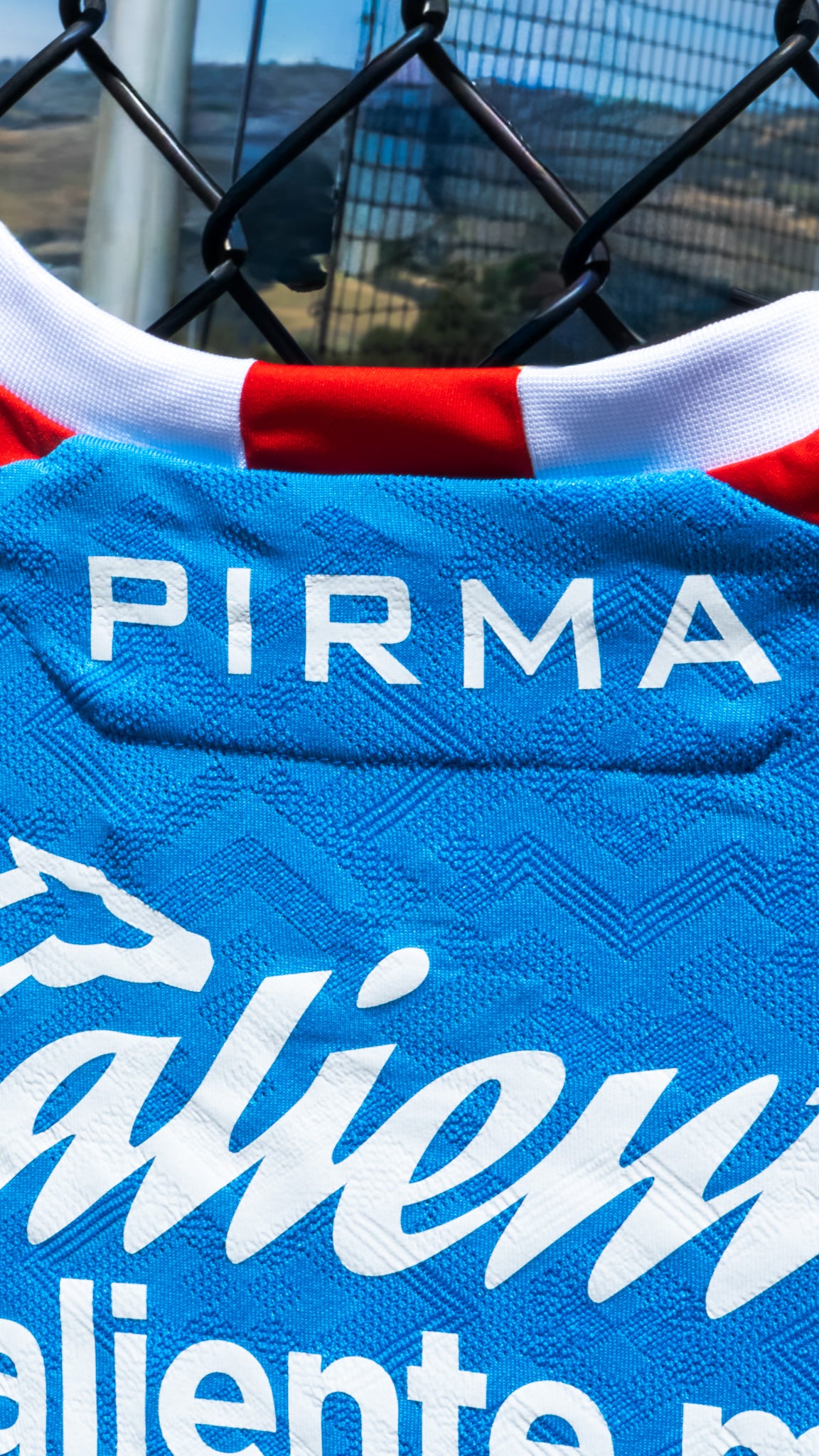 Close-up of a sports jersey with 'PIRMA' branding and visible text.